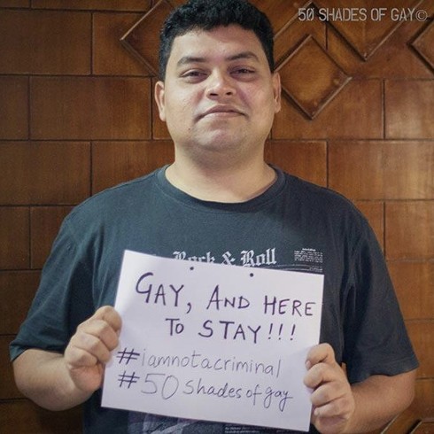 Navin Noronha holding a whiteboard that reads Gay, and here to stay